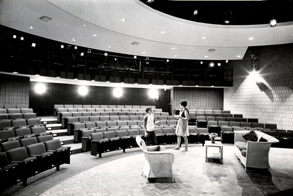 Interior view of the John Michael Kohler Arts Center, with two individuals on stage, and a scene set.