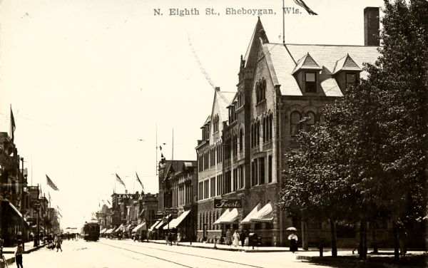 View across North Eighth Street, lined with storefronts and pedestrians. Caption reads: "N. Eighth St., Sheboygan, Wis."