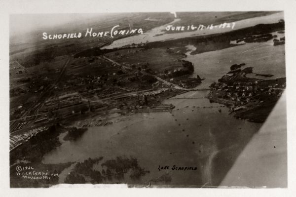 Aerial view with Wisconsin River. Caption reads: "Schofield Home Coming June 16-17-18-1927". The wing of an airplane is in the right foreground.