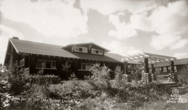 Exterior view of the Buck Inn at Lost Lake Resort. Caption reads: "Buck Inn At Lost Lake Resort, Sayner, Wis."