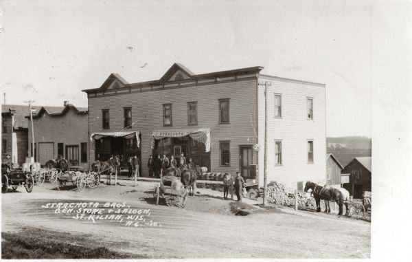 Exterior view of the Strachota Brothers general store and saloon, including people and horses. Caption reads: "Strachota Bros. Gen Store & Saloon, St. Kilian, Wis."