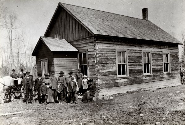 Exterior view of the Raspberry School with a group of adults and children standing outside its entrance.