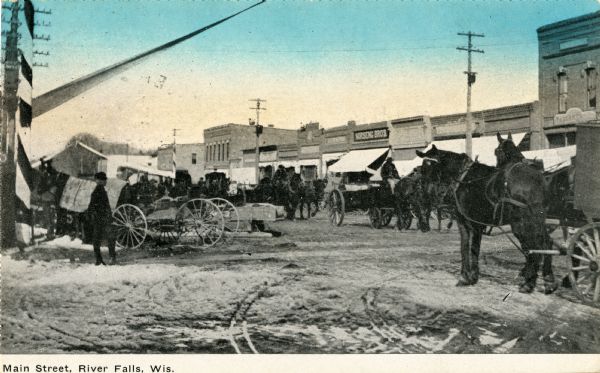 Men are standing with horse-drawn wagons on Main Street. Caption reads: "Main Street, River Falls, Wis."