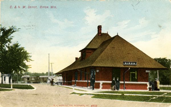 View of the Chicago and Northwestern Railway depot with several people standing outside around it. Caption reads: "C. & N. W. Depot, Ripon, Wis."