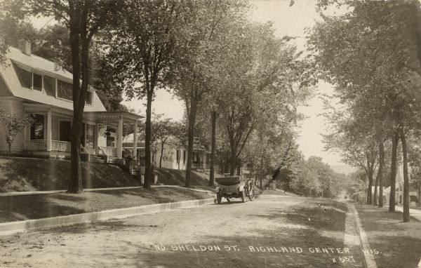 View along right curb towards the left side of the tree-lined street, where an automobile is parked. Caption reads: "No. Sheldon St. Richland Center Wis."