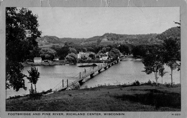 Elevated view of a footbridge over Pine River. Caption reads: "Footbridge and Pine River, Richland Center, Wisconsin".
