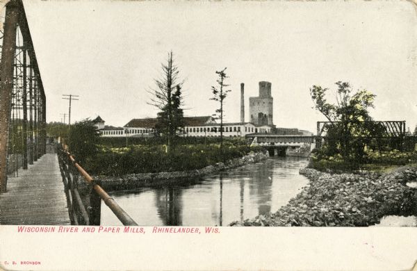View from bridge looking towards the paper mill and railroad bridge on the Wisconsin River outside of Rhinelander. Caption reads: "Wisconsin River and Paper Mills, Rhinelander, Wis."