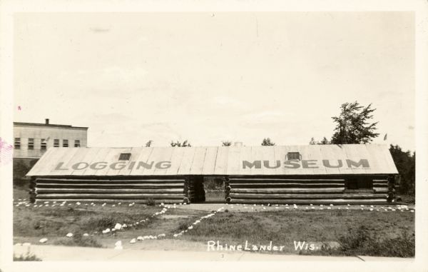 Logging Museum in Rhinelander. A long building has a sign on the roof that reads: "Logging Museum".