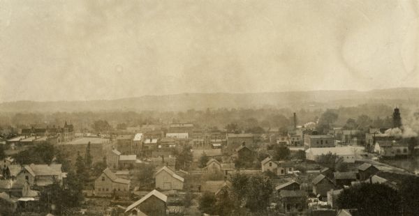Elevated view of multiple homes and buildings. Hills are in the distance.