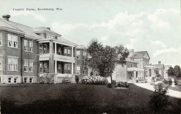 View across lawn towards buildings. Caption reads: "County Farm, Reedsburg, Wis."
