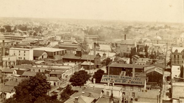 Elevated view from tower of the Racine Court House looking north. A note at bottom center on the building of a roof reads, in part: "1st. Presby. Church. 1842. 1869 Wis. St. School."