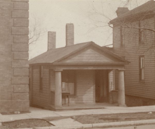 View from street towards Dr. Thompson's office, a small building with a front porch framed by two columns, and located between two larger buildings.