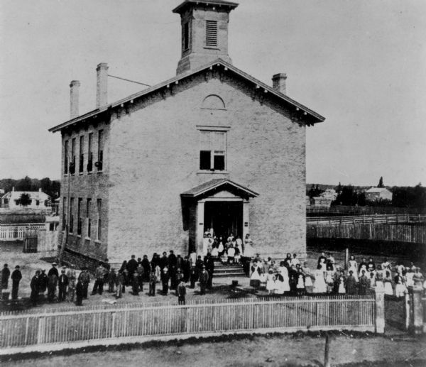 Elevated view of the Third Ward school, with students in front.