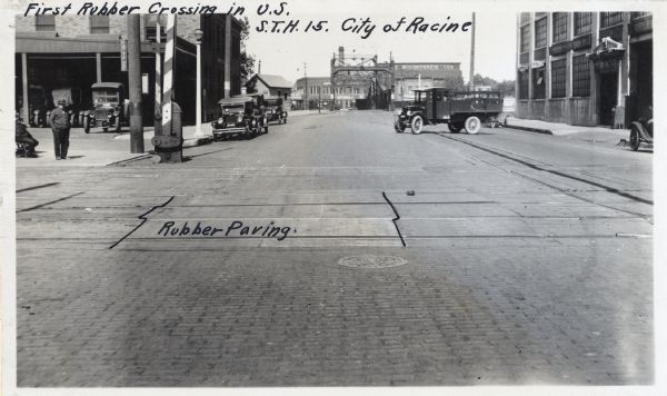 View of the railroad crossing where rubber paving was used for the first time in the United States. Caption at top reads: "First Rubber Crossing in U.S. S.T.H. 15. City of Racine." In the center on the crossing it reads: "Rubber Paving."