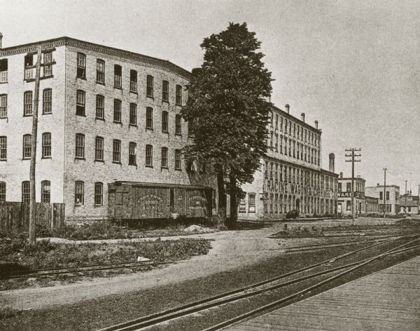 Exterior view of the Racine Wagon Works building with railroad tracks in the foreground.