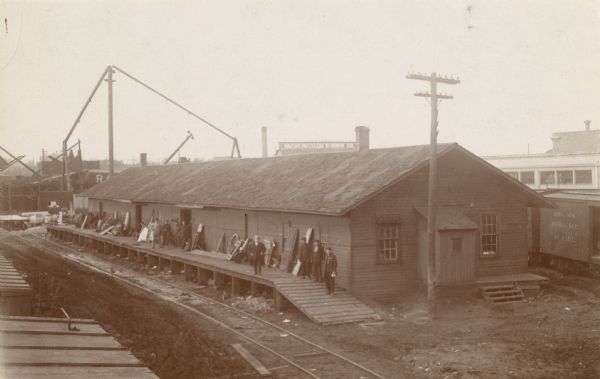 View of the Racine and Mississippi freight and passenger depot with multiple individuals lined up on the platform.