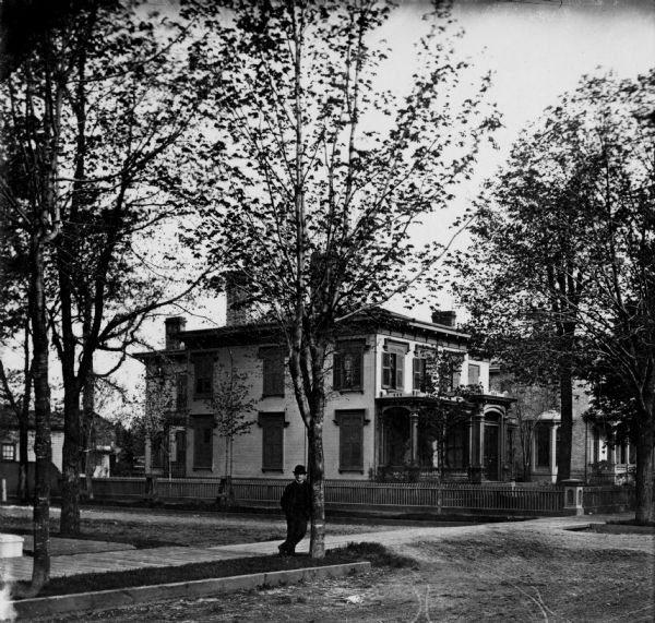 The F.M. Knapp residence, northwest corner of Main and 10th Streets. A man is standing and leaning on a tree on the terrace.