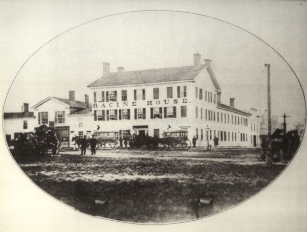 Exterior view of the Racine House with multiple horse-drawn wagons and figures standing in front.