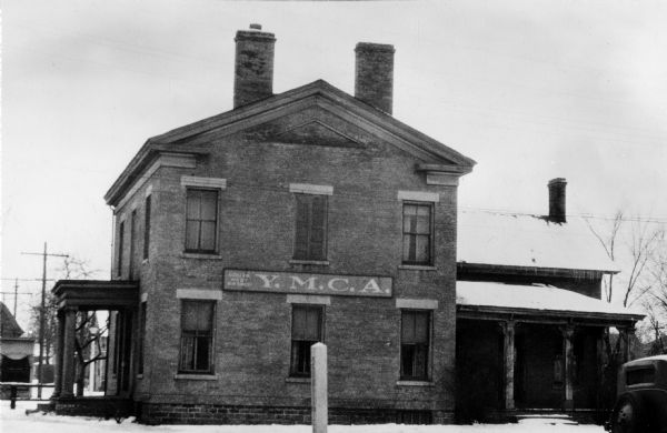 Exterior view of the east elevation of the Fratt house. The sign on the building reads: "Y.M.C.A."