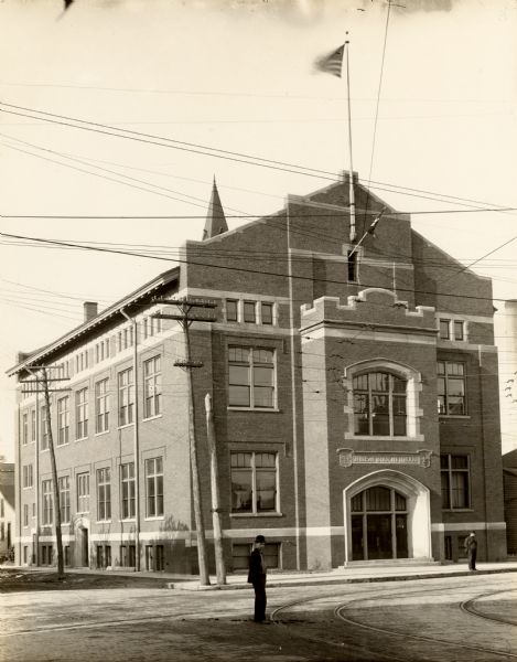 Exterior view of the Danish Brotherhood building with two men standing, on the sidewalk, and one in the street.
