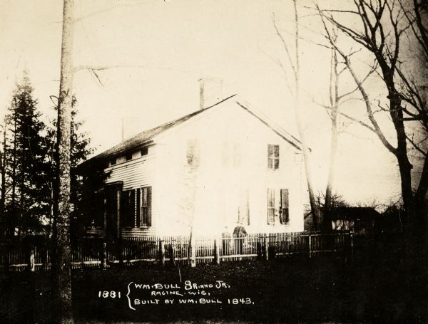 The William Bull house, built by William Bull Sr. in 1843. A man and boy are standing behind the fence. Caption reads: "1881 {Wm. Bull Sr. and Jr. Racine, Wis. Built by Wm. Bull 1843."