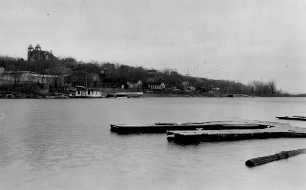 View of town on opposite shoreline, and piers in the foreground on the right. Taken from the Burlington Railroad bridge.