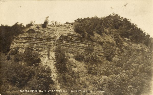 View of bluff taken from below. Caption reads: "Rattlesnake Bluff at Loddes Mill Sauk Co., Wis."