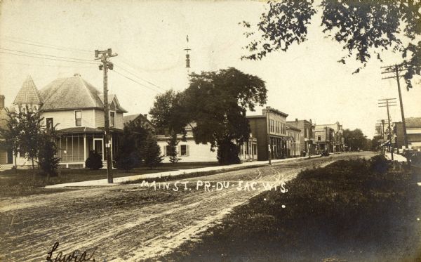 View from right side of street towards houses and retail stores lining the left side of Main Street. Caption reads: "Main St. Pr.-Du-Sac, Wis."