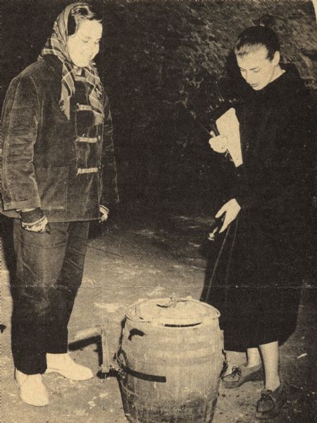 Two young women looking at a wine making tool. Winery operated from 1867 to 1899. It later became a dance hall. Excerpt from Sauk Prairie Star, Sauk City, 18 February, 1960. Winery bought in 1972 by Robert P. Wollersheim and now operated as the Wollersheim Winery.
