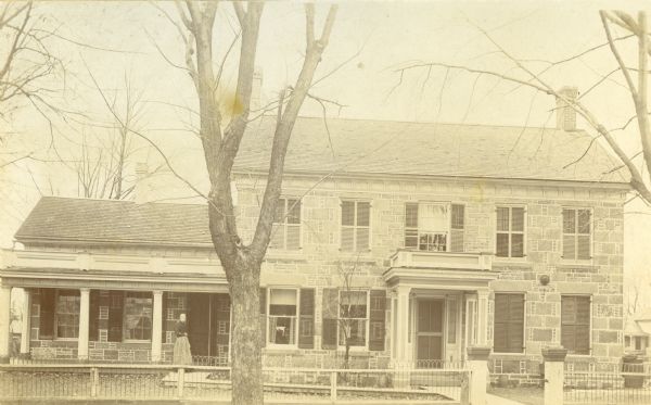 Front view of Cummings-Cooper house with woman standing in front. The house was owned in 1940 by Mrs. H.F. Leindorff. The house was built in 1857.