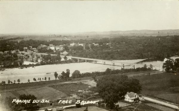Elevated view of bridge over Wisconsin River built in 1921 to take the place of the old wooden bridge when it became condemned. Caption reads: "Prairie Du Sac Free Bridge."