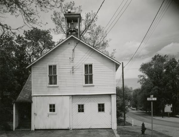 View towards the Fire Station, with garage doors and a bell tower on the roof. A road is on the right.