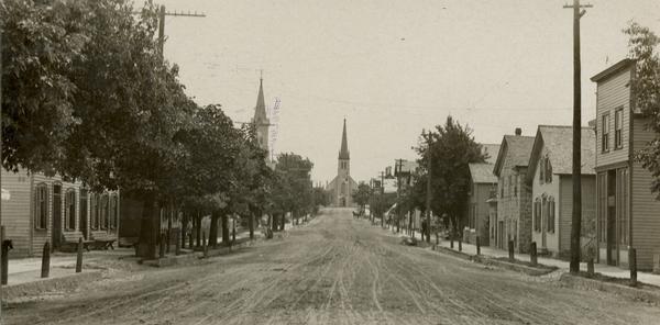 View down center of unpaved street in Cedarburg, with a large church at the far end.