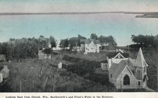 Elevated view with buildings and a church in the foreground. Caption reads: "Looking East from Chetek, Wis., Southworth's and Flinn's Point in the Distance."