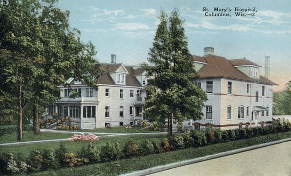 Lawn, trees and blooming flowers in front of St. Mary's Hospital. Caption reads: "St. Mary's Hospital, Columbus, Wis."