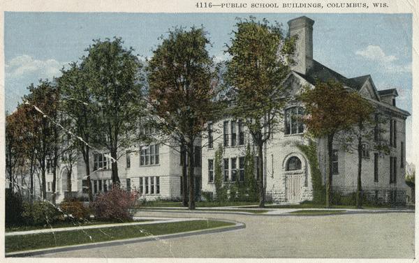 View from road toward the Public school buildings. Caption reads: "Public School Buildings, Columbus, Wis."