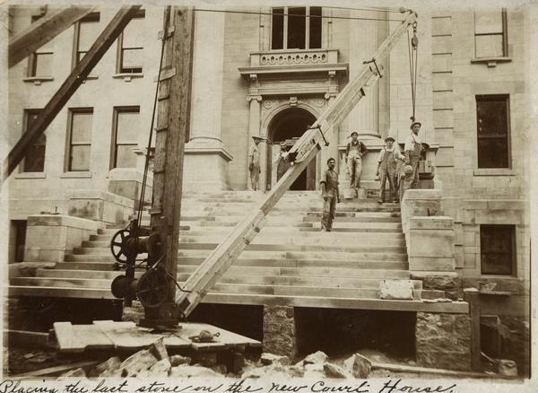 View of the Lafayette County Courthouse during construction. The men are placing the last stone into position.