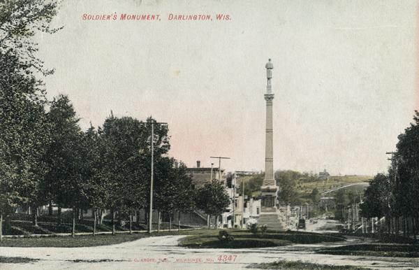 View down street towards Soldiers' Monument. Caption reads: "Soldiers' Monument, Darlington, Wis."