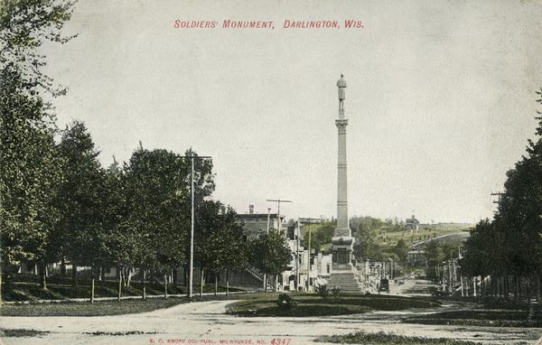 View down road looking towards Soldiers' Monument and town beyond. Caption reads: "Soldiers' Monument, Darlington, Wis."