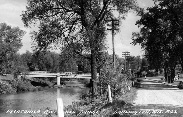 View down road, with the Pecatonica River and a bridge on the left. Caption reads: "Pecatonica River and Bridge, Darlington, Wis."