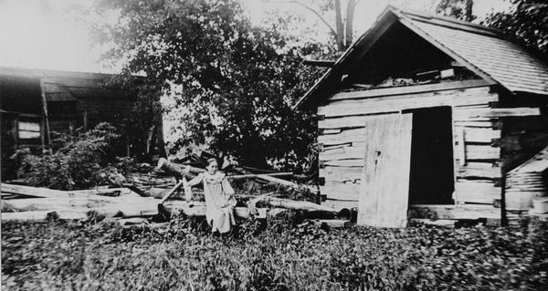 A girl sits on a log next to Eleazer William's log cabin site.