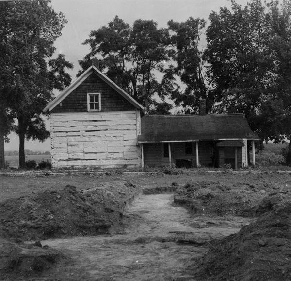 Replica of Eleazer William's log cabin, with an archeological dig being conducted in front of the cabin.