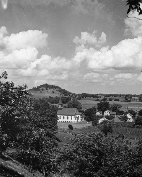 Church, several houses and field from a hill.