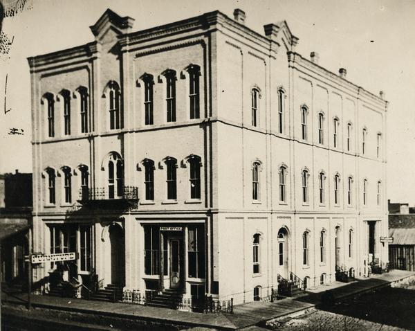 Elevated view of a large building on a street corner. There is a small "Post Office" sign on the right side of the building, and a larger "FURNITURE" sign to the left of it.