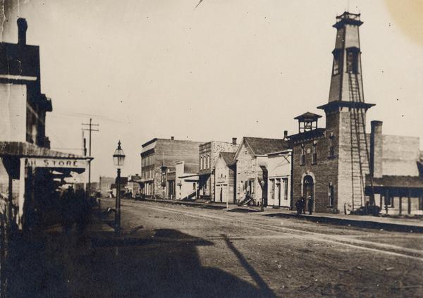 Water street, before the fire of the 1880's, from the corner of Fifth avenue, looking east with storefronts and fire engine house.