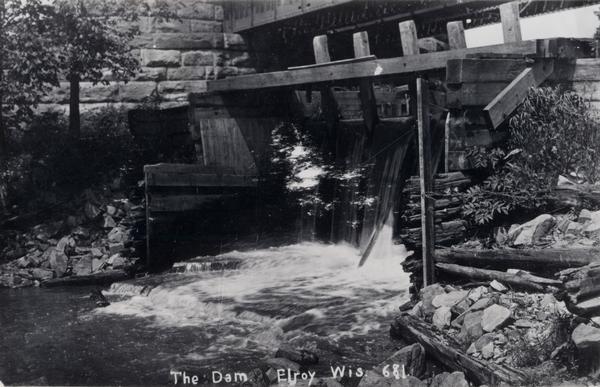 View from shoreline toward the lower part of a dam. Caption reads: "Dam in Elroy, Wis."