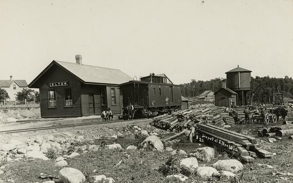 Chicago and Northwestern railroad staton in Elton, with lumber stacked on the ground.
