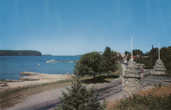 Eagle Harbor, looking west, with boats anchored in the harbor. In the foreground are the stone pillars of the village fire station.