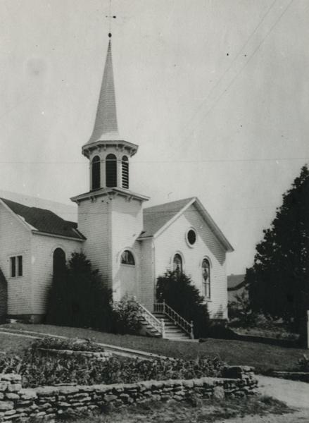 Exterior view of the front of a Moravian Church with a steeple.