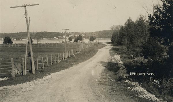 A lane in Ephraim with power lines lining the road. There is a body of water in the distance with houses on the far shoreline.